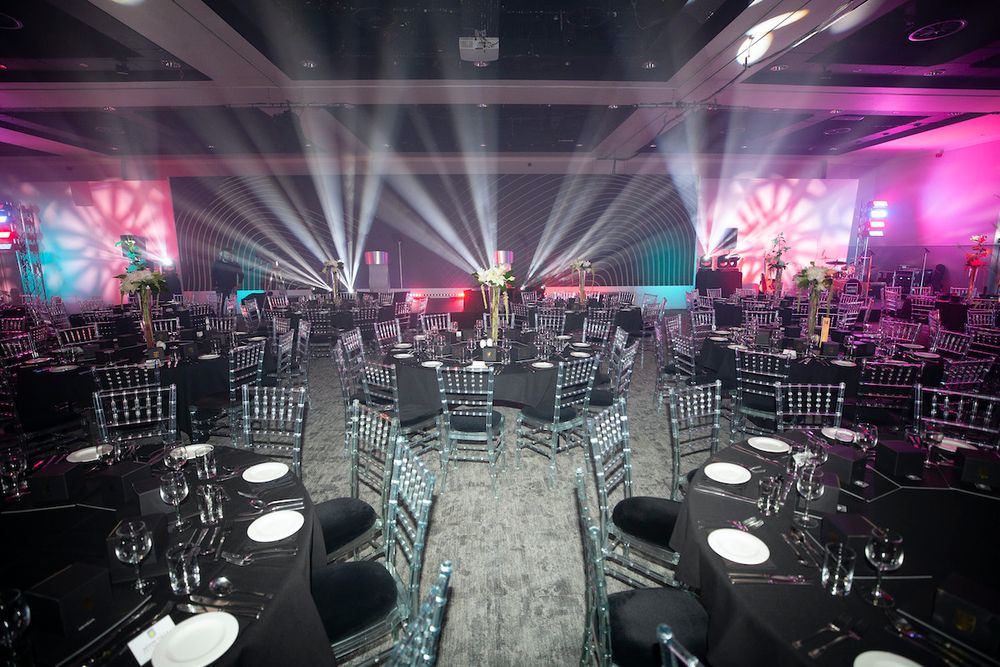 Elegant gala setup in Hall Green Stadium with black tables and transparent chairs.