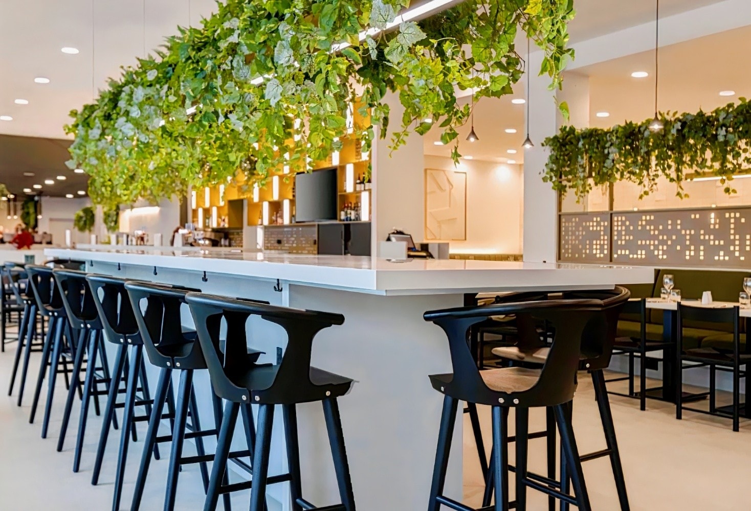 Modern bar area with high stools and greenery, perfect for networking events in Manchester. - Banner