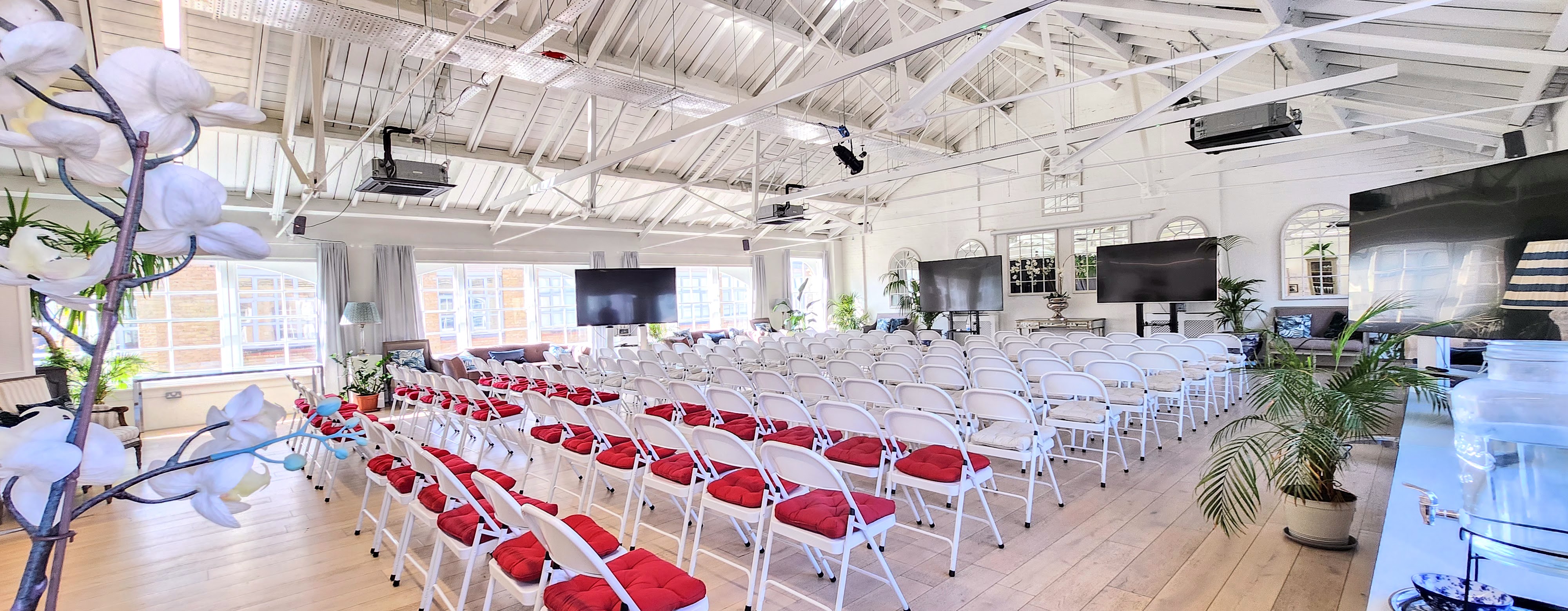 Event space with white chairs and red cushions, perfect for conferences or seminars.