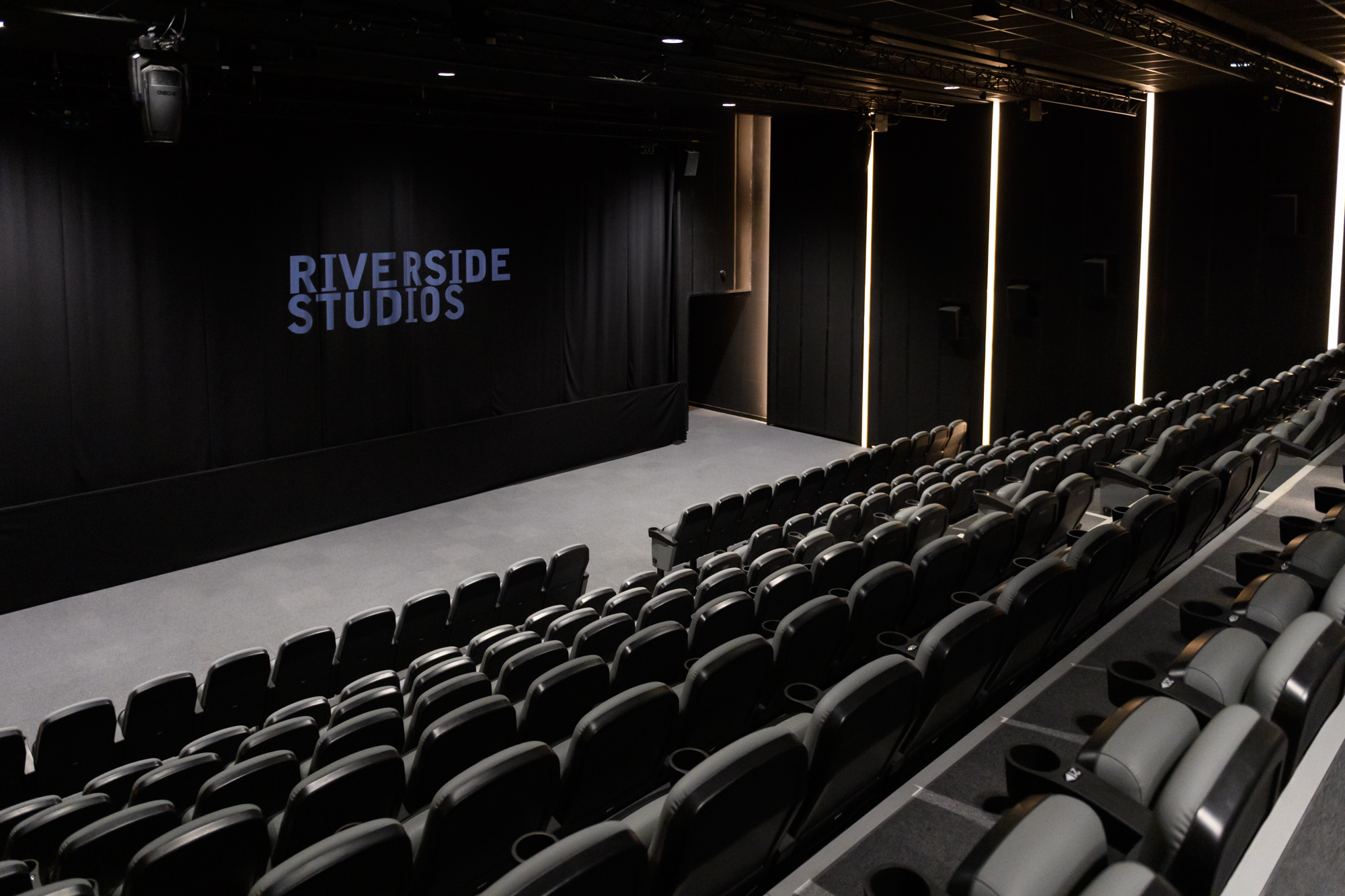 Modern auditorium with tiered seating at Riverside Studios for events and performances. - Banner