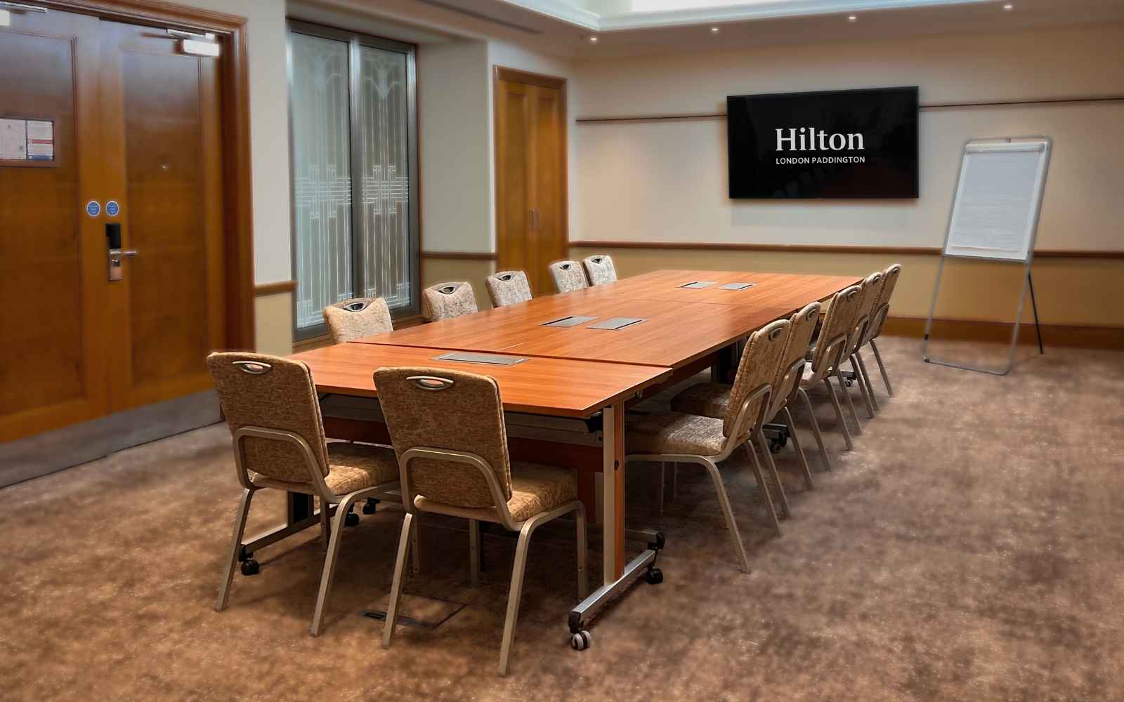 Meeting room at Hilton London Paddington with large table, ideal for corporate events.