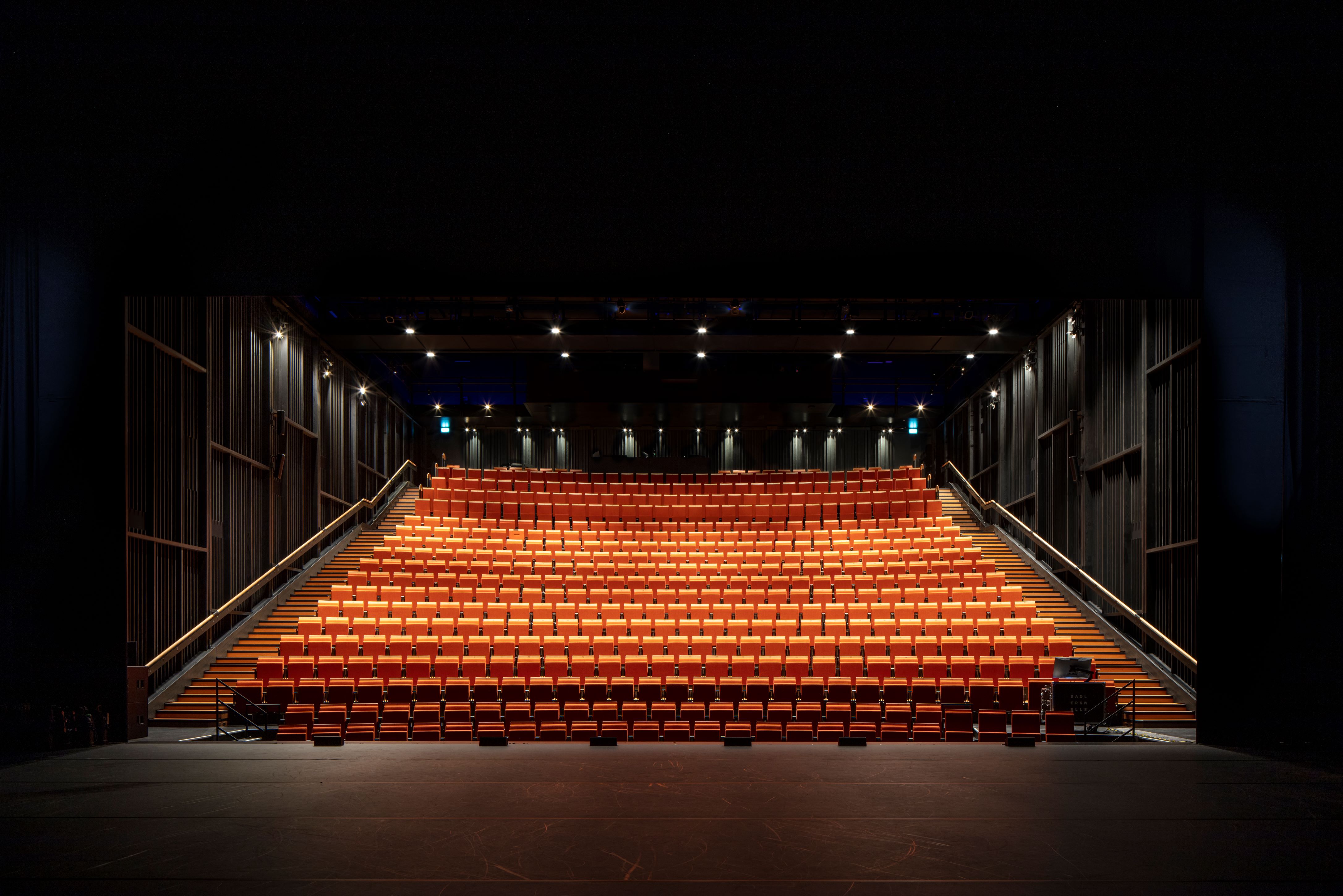 Empty tiered auditorium at Sadler's Wells East, ideal for presentations and performances.
