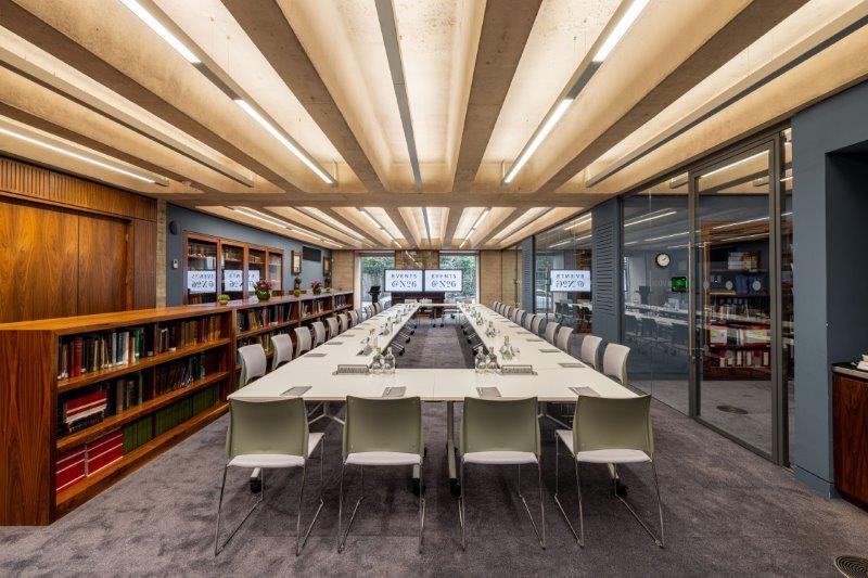 Modern library meeting room with sleek table, ideal for workshops and strategic meetings.