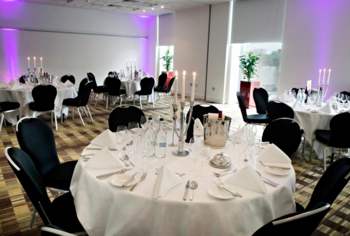 Modern banquet hall in Hilton Manchester Deansgate with black chairs for formal corporate events.
