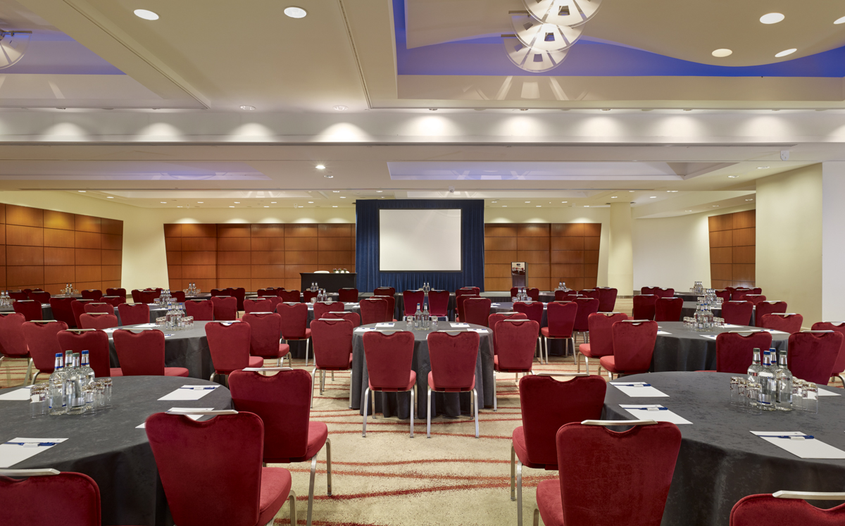 Victoria Suite at Park Plaza Victoria London, ideal for conferences with round tables and red chairs.