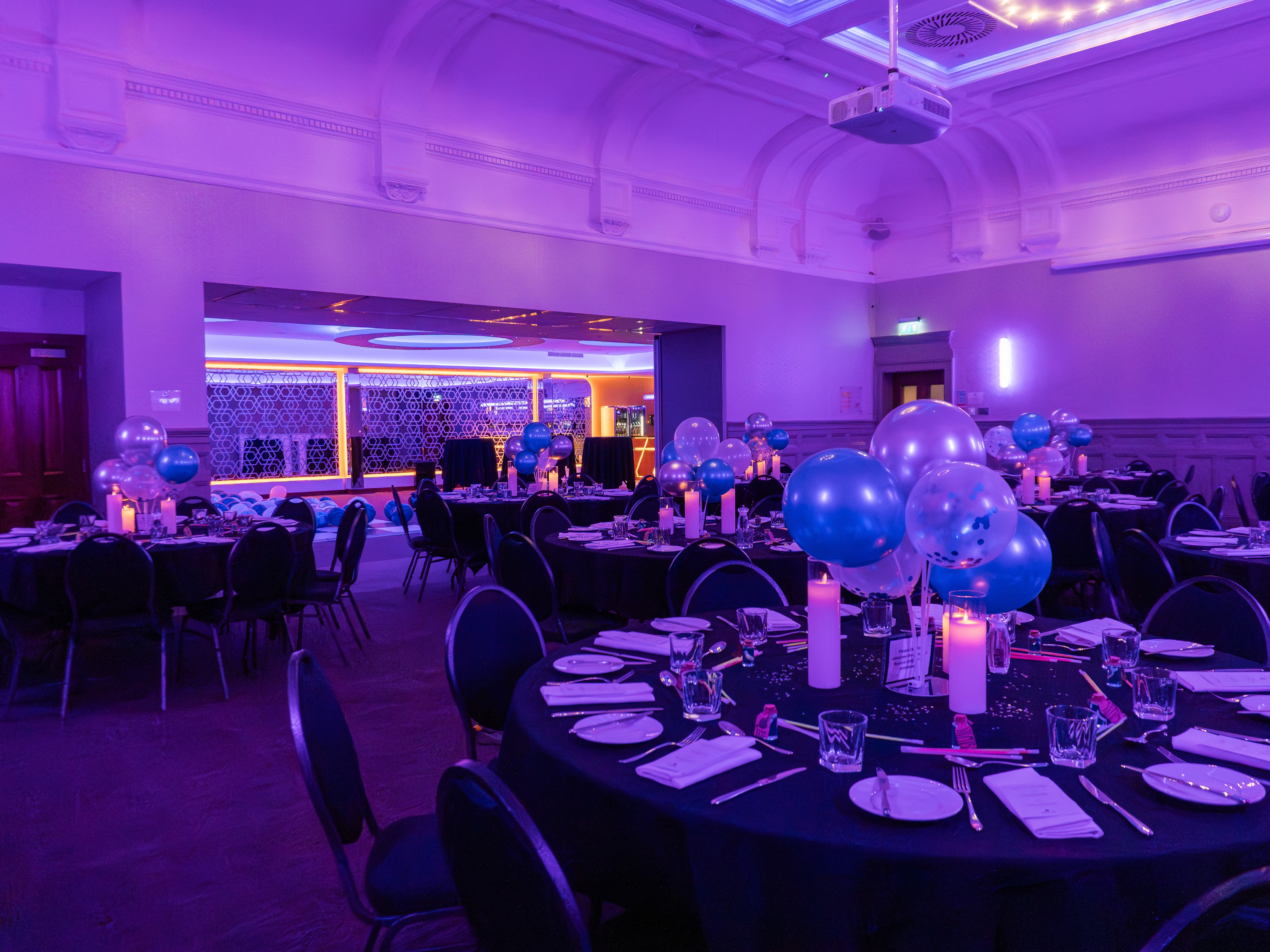 Elegant gala event space at The Broughton, featuring round tables and purple lighting.