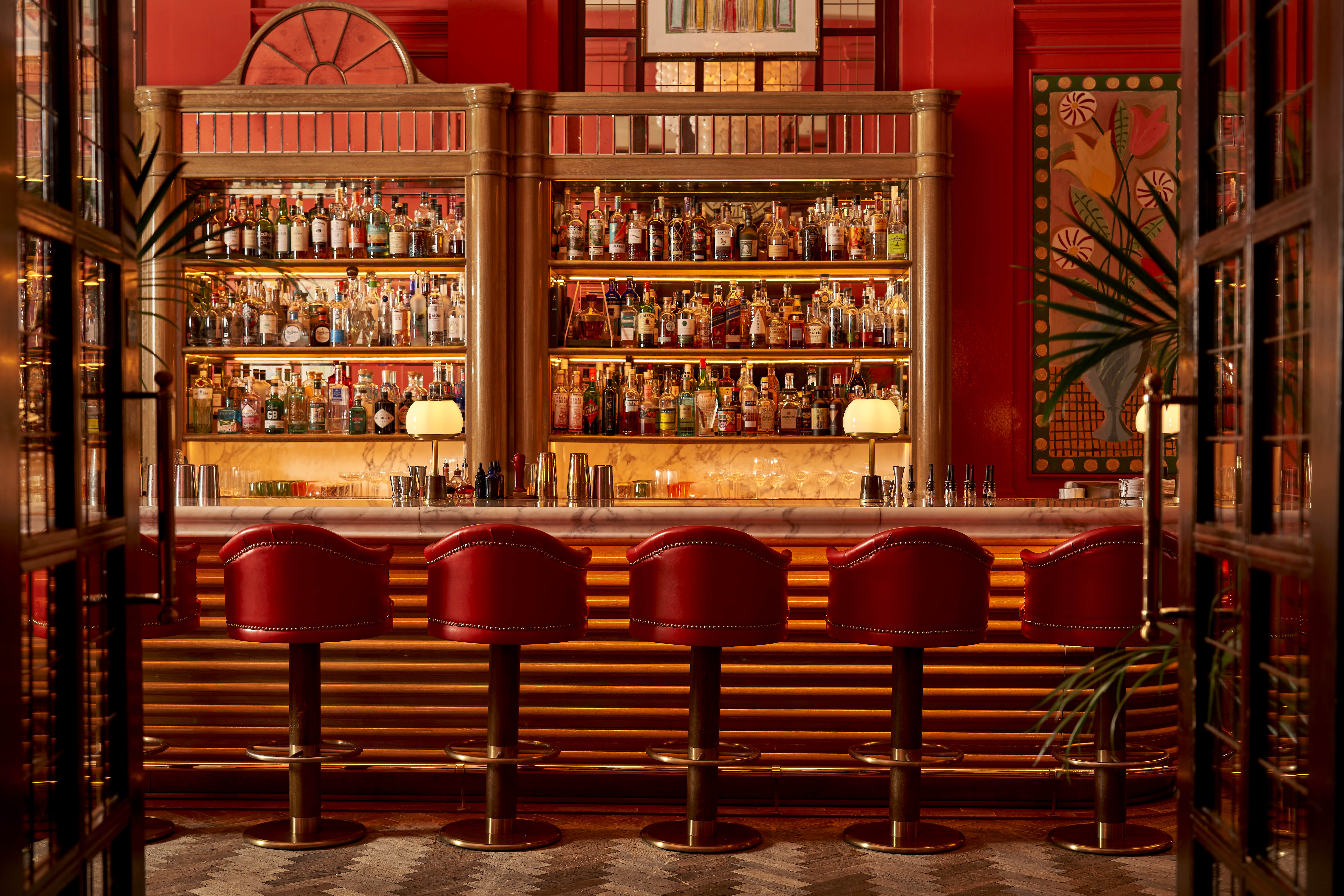 Stylish Coral Room bar with rich red walls, perfect for cocktail receptions and networking. - Banner