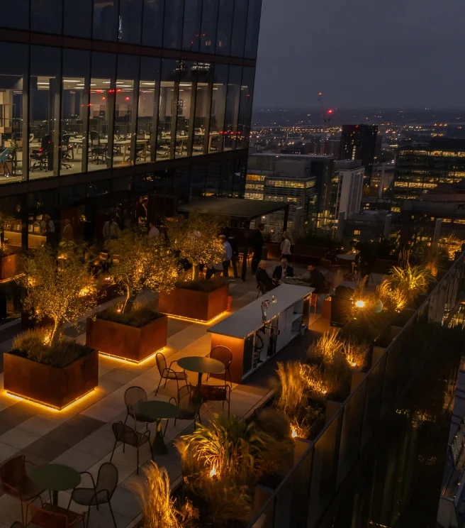 Modern rooftop meeting venue with urban skyline for corporate cocktail reception and networking.