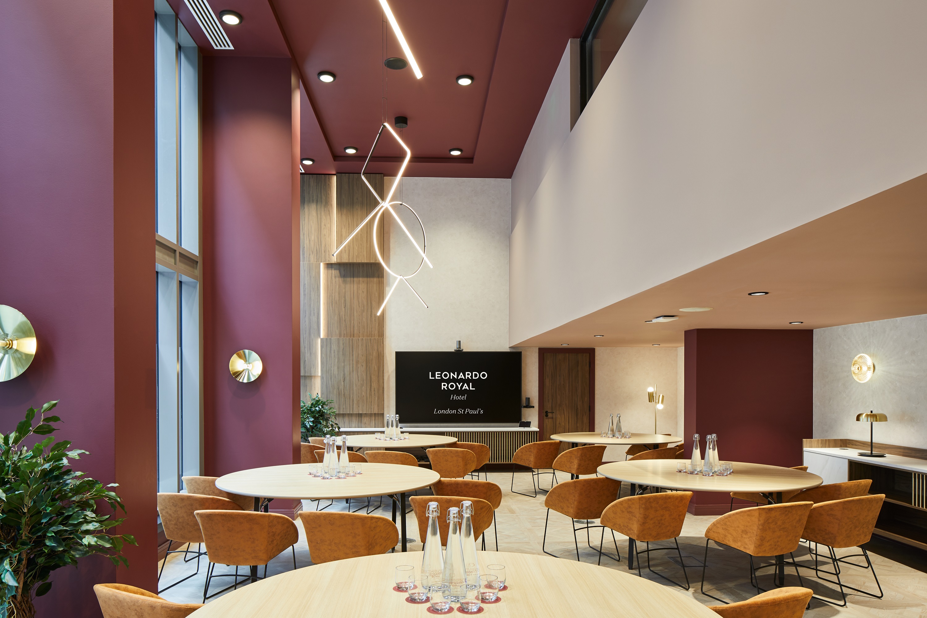 Modern meeting room at Leonardo Royal Hotel, featuring circular tables and natural light.