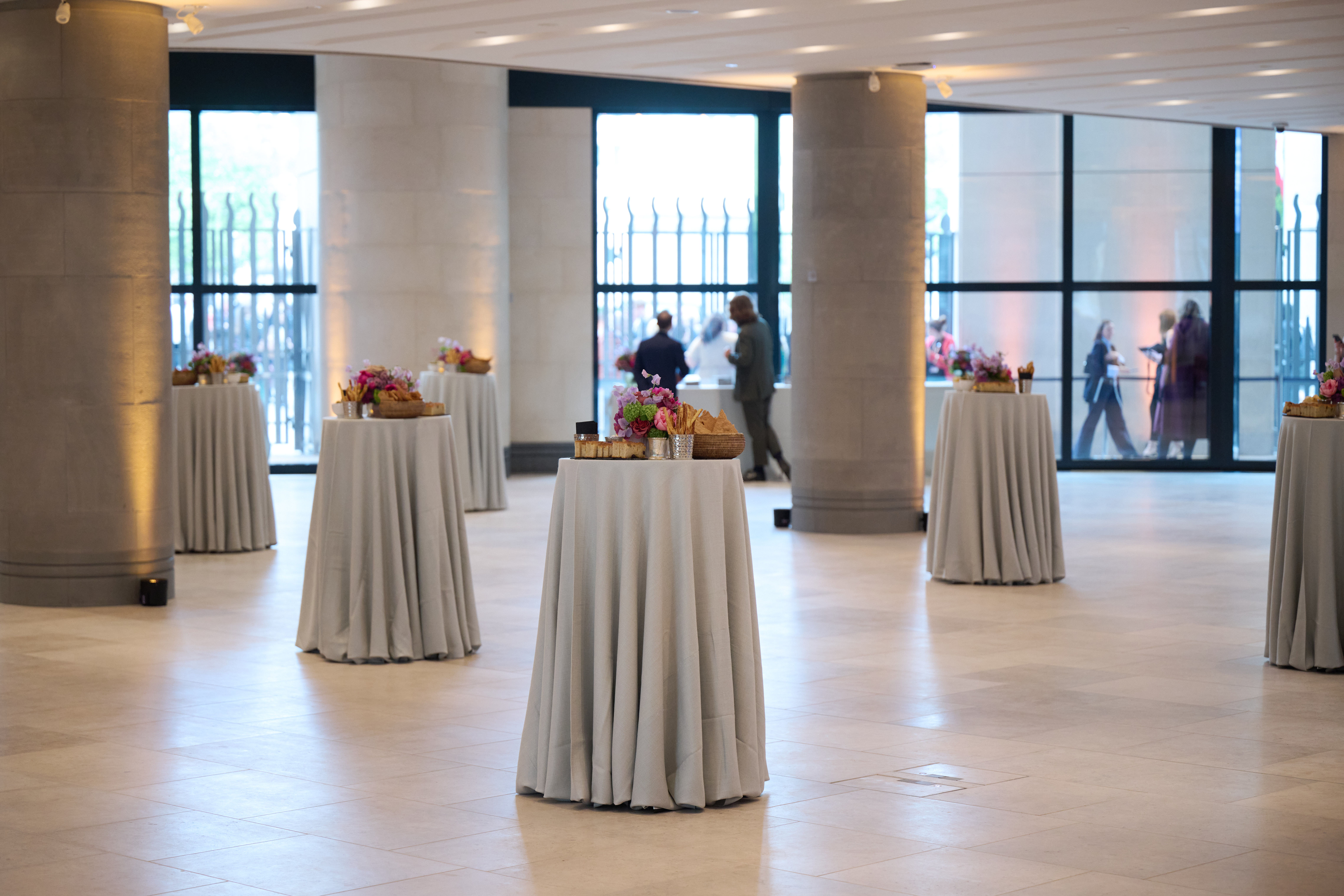 Sainsbury Wing Foyer event space with cocktail tables and floral arrangements, ideal for gatherings.