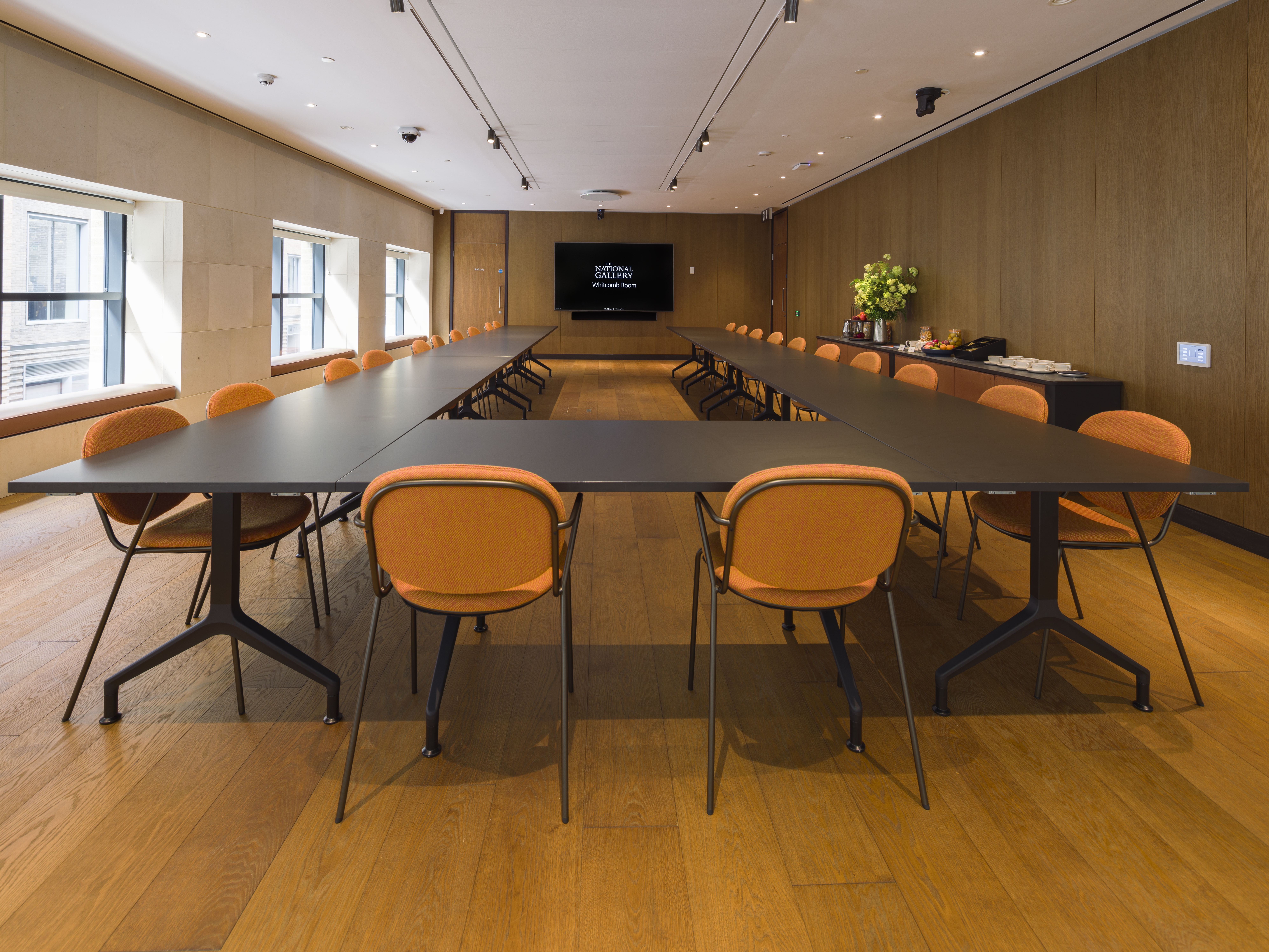 Modern meeting room with orange chairs for collaborative events at The National Gallery.