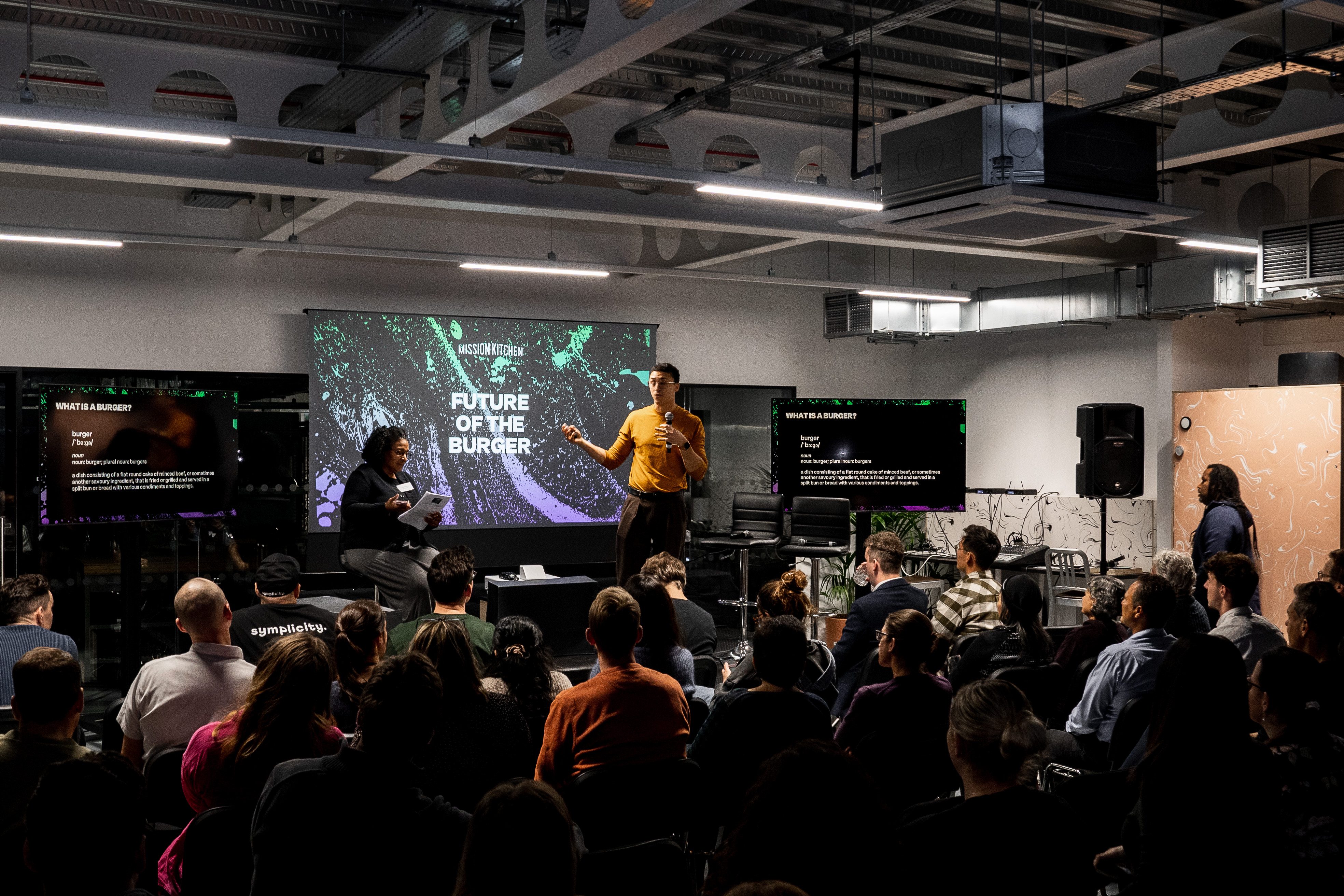 Engaging speaker in modern Glass Room event space for workshops and panel discussions.