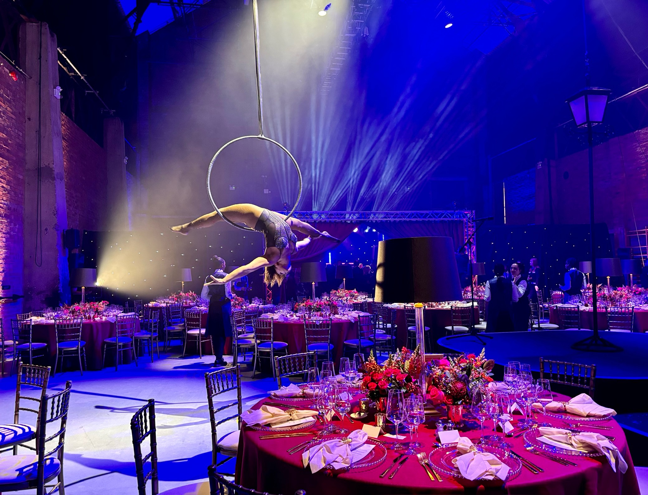 Aerial performers at a Shoreditch Electric gala dinner with dramatic stage lighting.