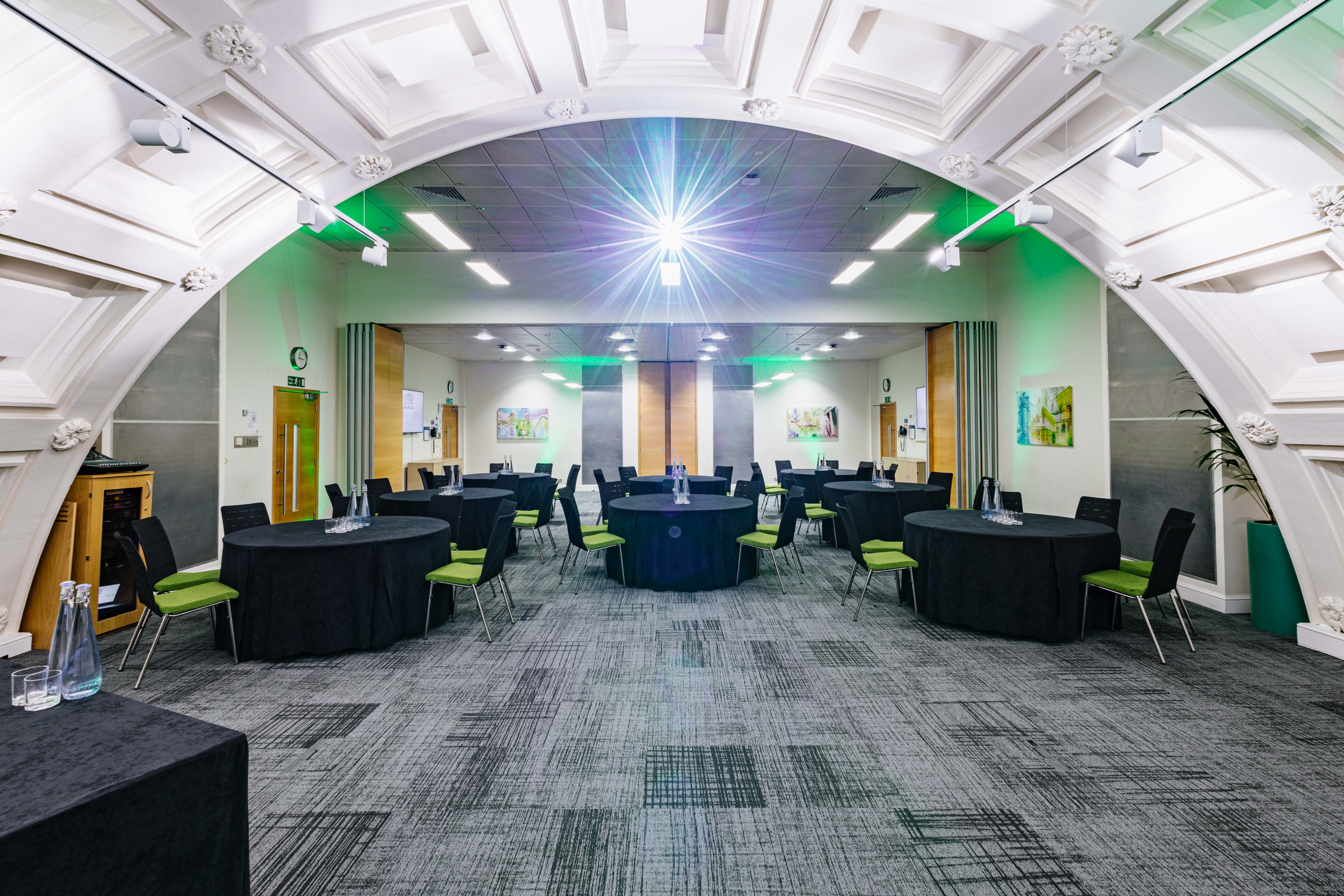 Low-Impact DDR event space with black tables, green chairs, perfect for conferences.