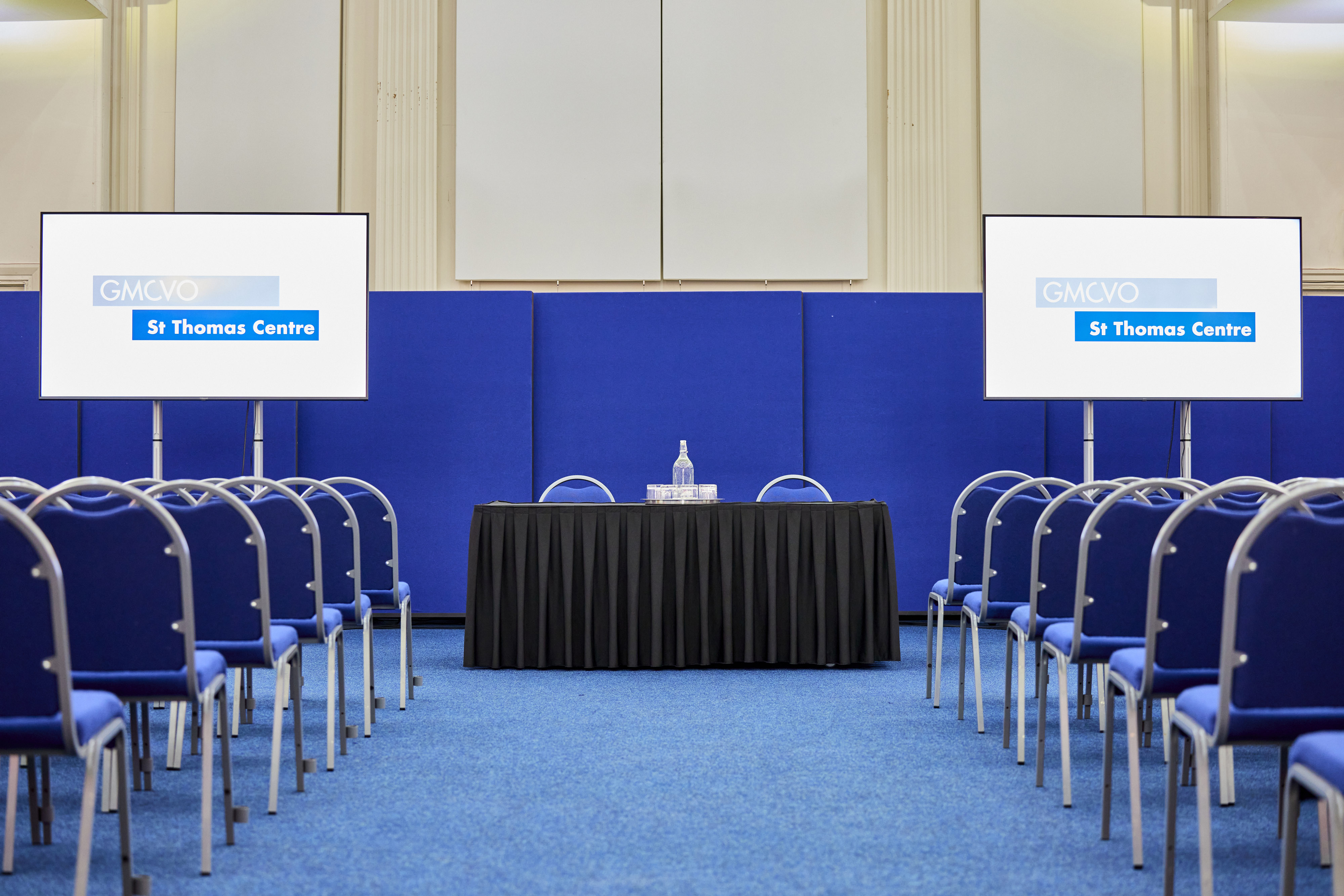 Main Hall at St Thomas Centre with central table, blue chairs for events and presentations.