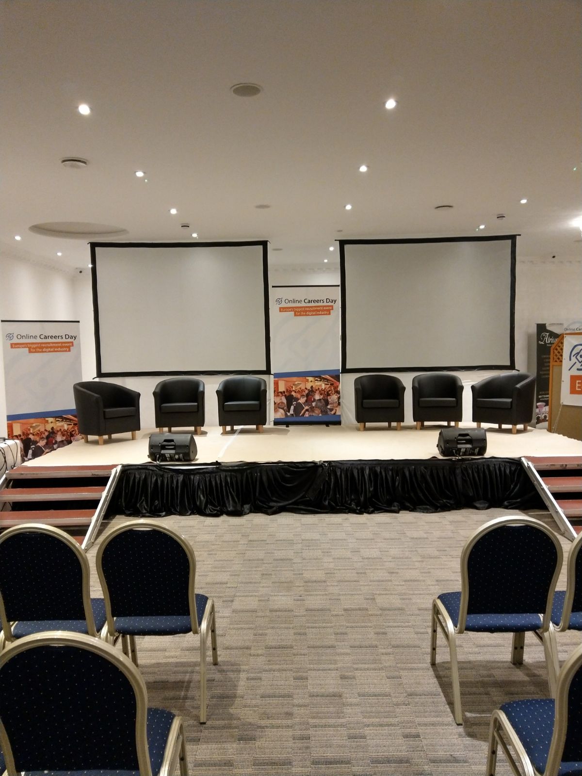 Main Hall in The Atrium London with event stage, screens, and chairs for presentations.