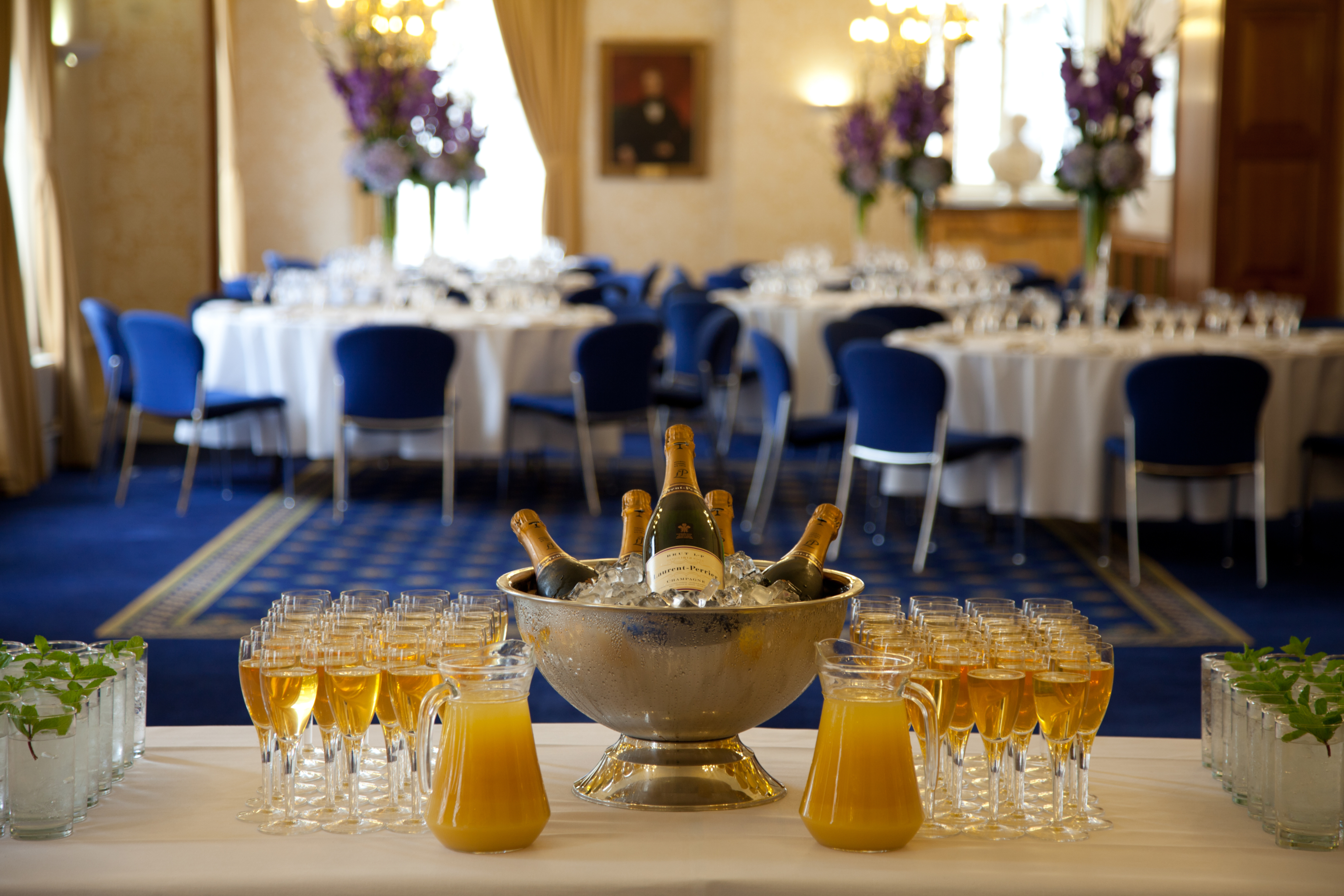 Elegant event space with round tables and blue chairs for formal receptions.