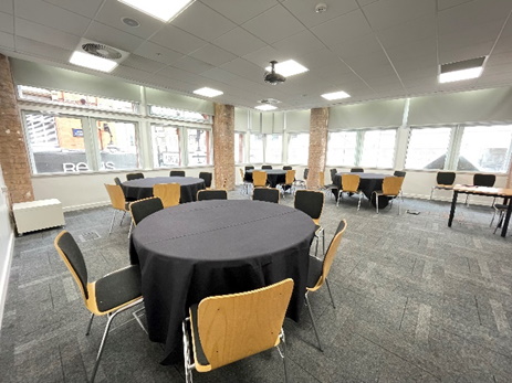 Versatile meeting space with round tables and natural light in Birmingham for events.